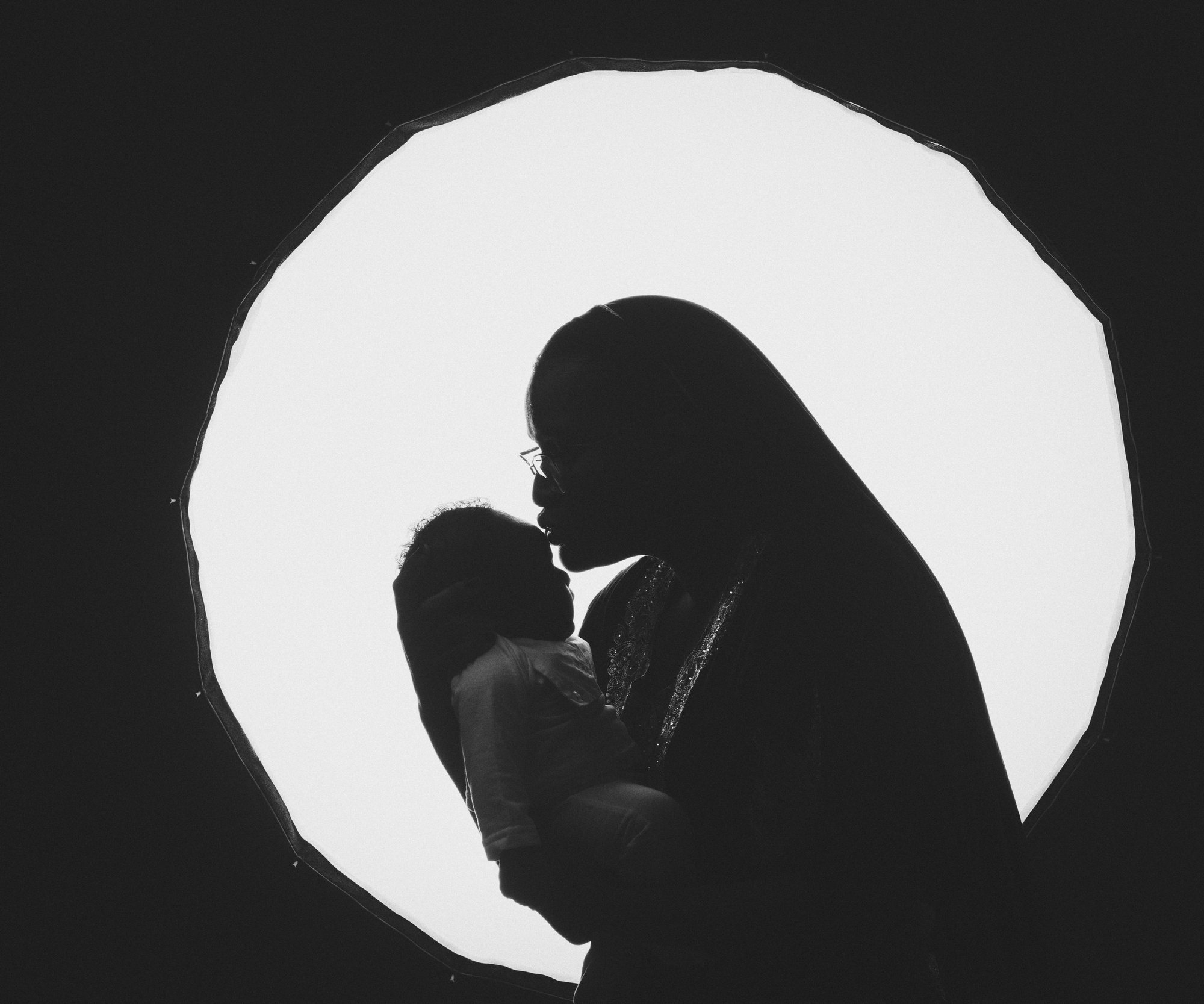 Silhouette of a mother cradling her newborn against a crescent moon